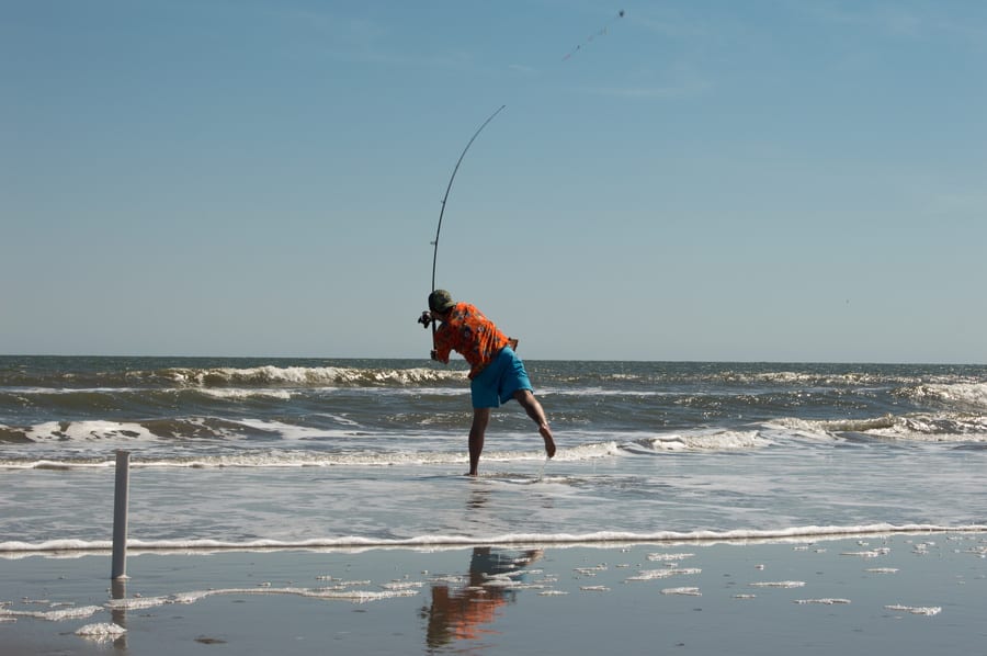 surf fishing photo of a man casting into the surf
